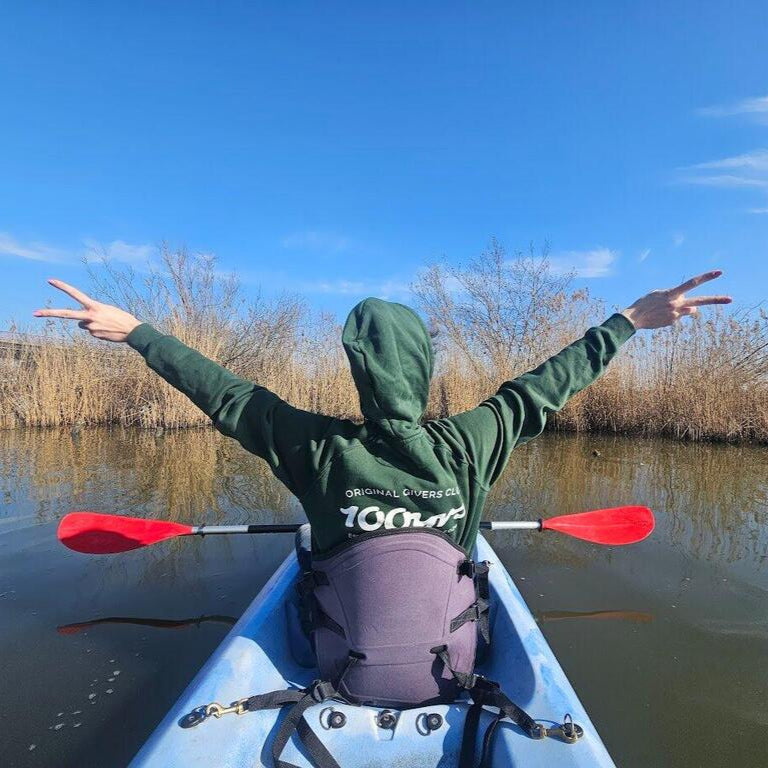 A woman on a canoe wearing a green raglan hoodie